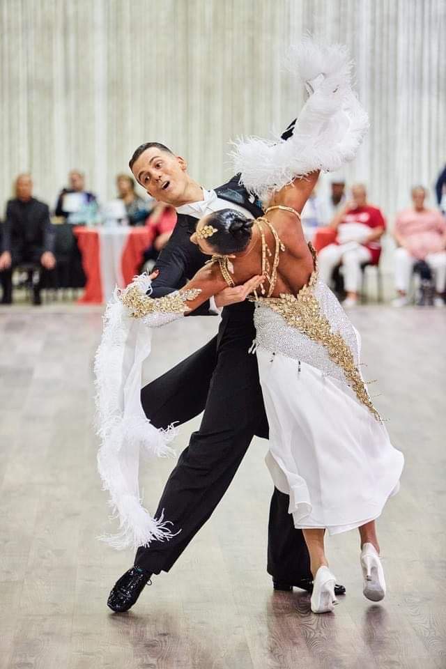 Veronika’s large, feathered gauntlets and floats, on this lovely white and gold dress, are well paired with a slim skirt with a slanted hemline, and white shoes. This allows for a gorgeous topline with a stylish view of their beautiful footwork. Photo Courtesy of Earle Williamson and Veronika Myshko.